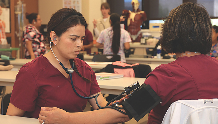 2 MPC medical assisting students practicing skills during class