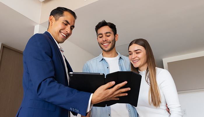 Real estate agent shows young couple information about a new home