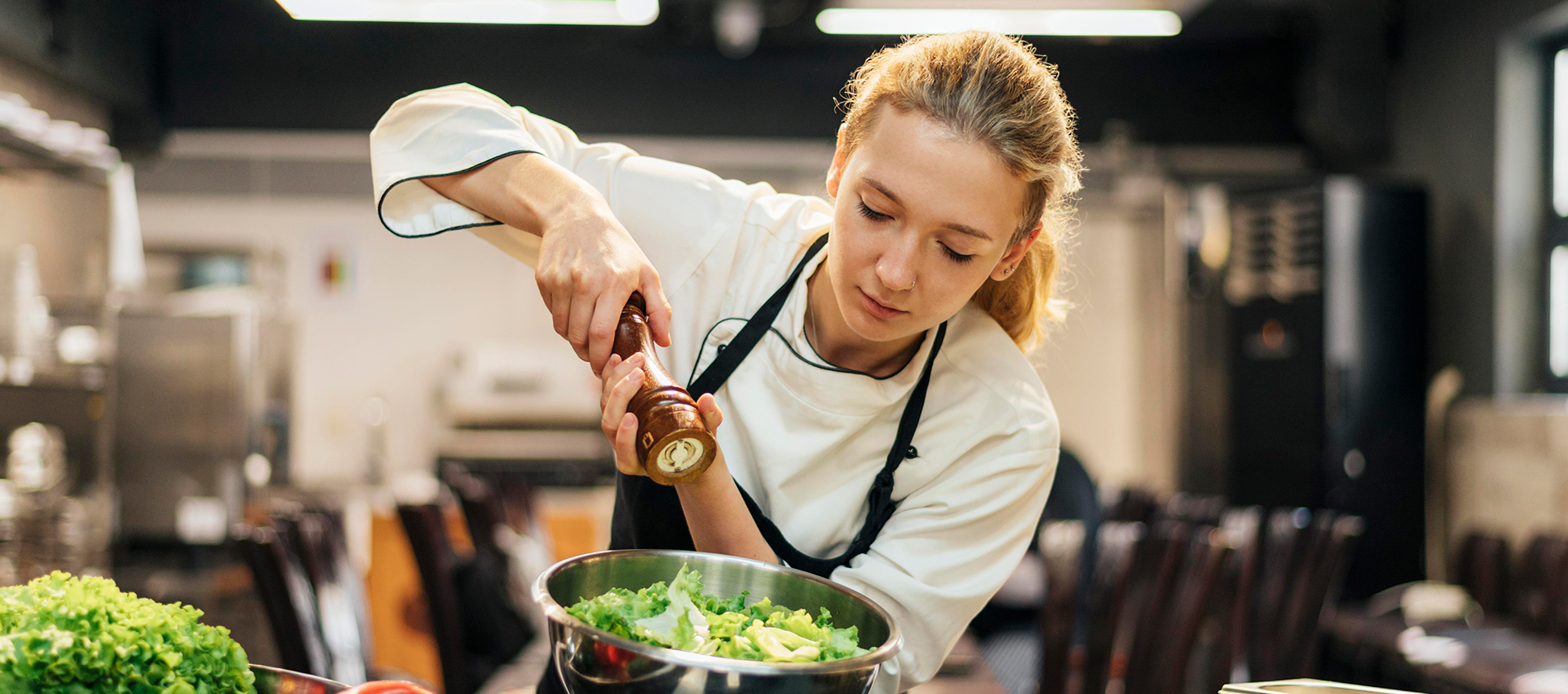 Hospitality student adds seasoning to salad