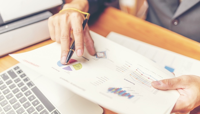 Person with Pen Analyzing Paper of Graphs