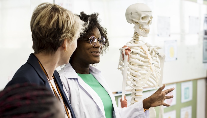 Anatomy Teacher Discussing the Human Skeleton in Front of Class