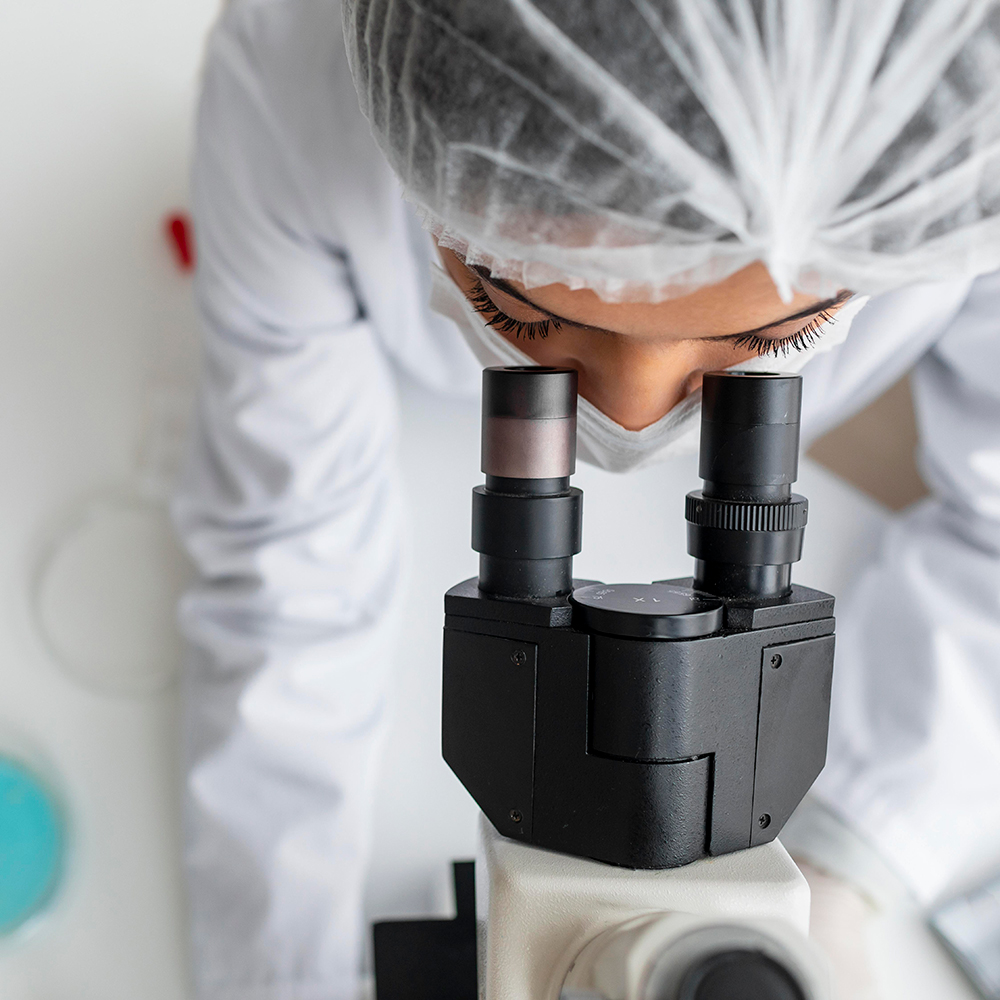 Lab technician looking at organisms through a microscope