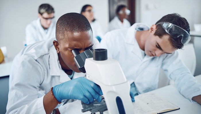 Chemistry Students Viewing Microscope and Taking Notes in Class