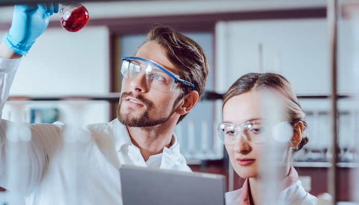 Chemists Mixing Chemicals and Taking Notes in Lab