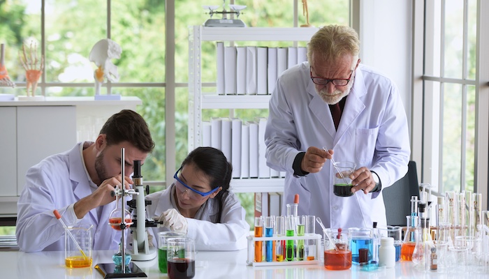 Three Chemists Mixing Chemicals in Lab