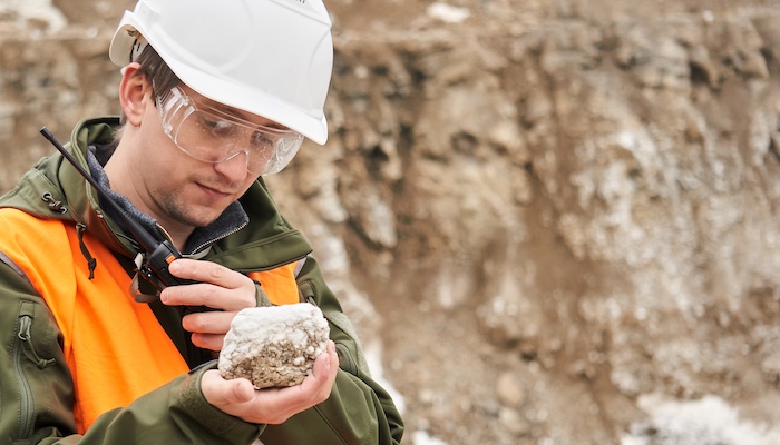 Geologist Analyzing Rock and Talking on Walkie-talkie