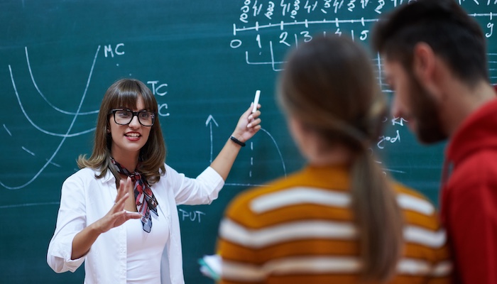 Teacher Explaining Math Problem and Showing Students Chalkboard