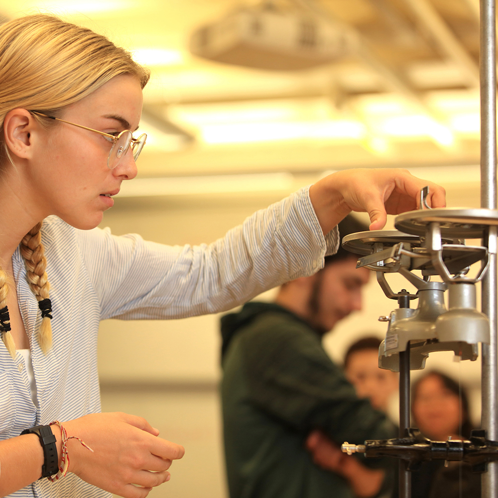 Physics student measures item on scale before conducting an experiment