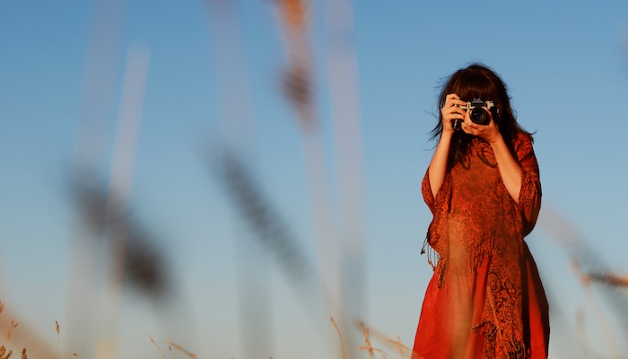 Woman Holding Camera Photographing in Field