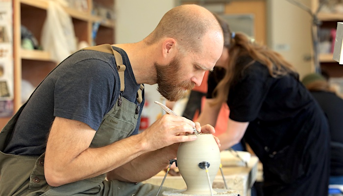 Ceramic Student Trimming Thrown Pot in Class