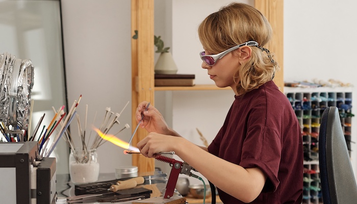 Glass Artist Wearing Protective Eyewear Using Hand Torch to Melt Glass Together