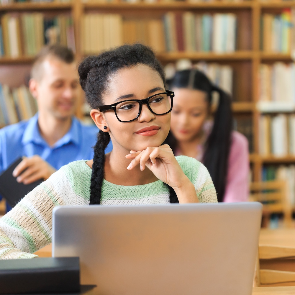 Young Student Listening in Class While Using Laptop