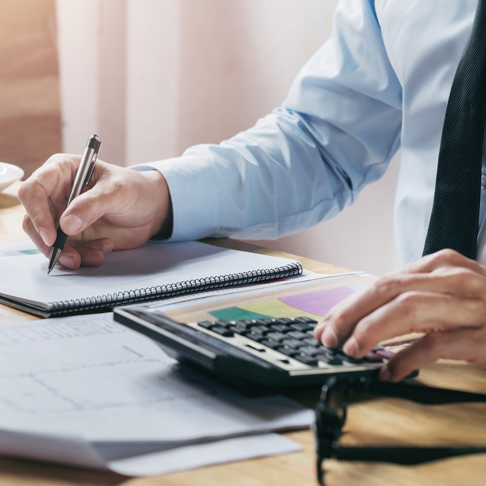 Accountant Using Calculator and Writing on Notepad