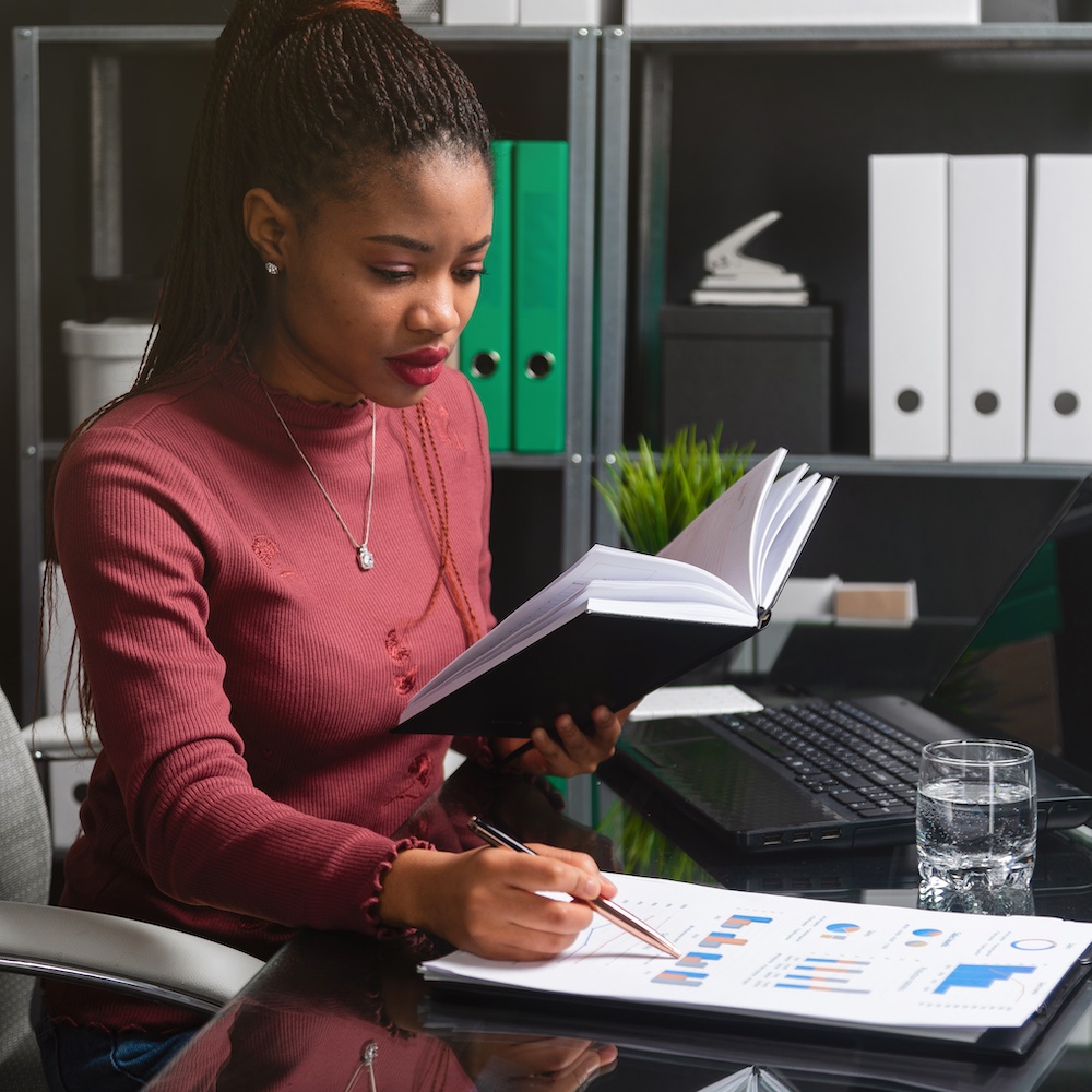 Business Administrator Reading Book and Writing Notes