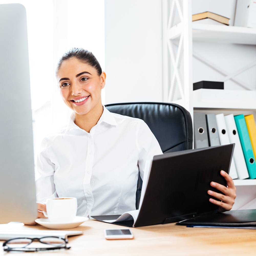 Office Administrator Working on Computer Holding Folder