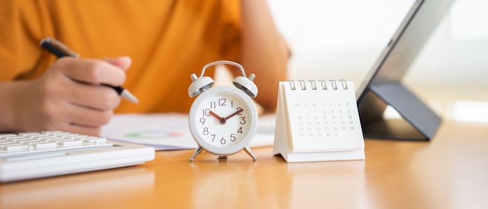 Person Working on Laptop with Clock and Calendar