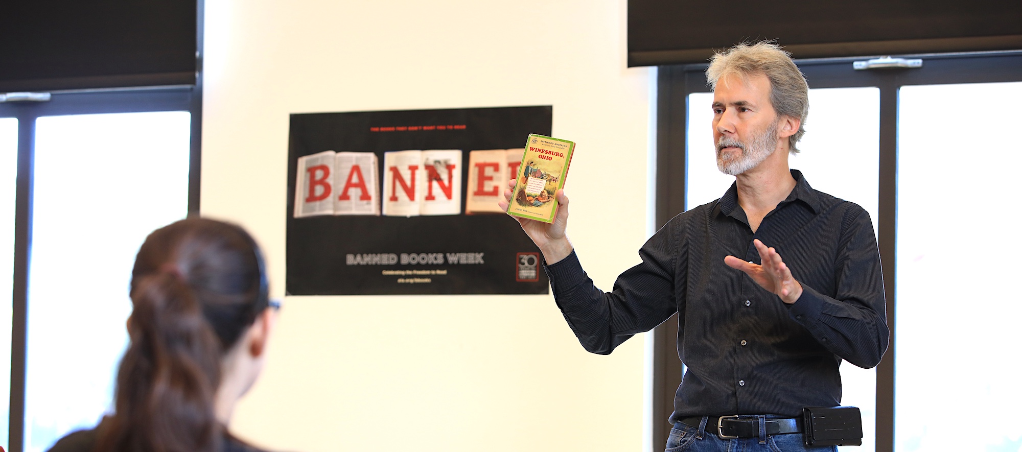 Professor Henry Marchand Holding Up Book During Banned Books Week Read-out