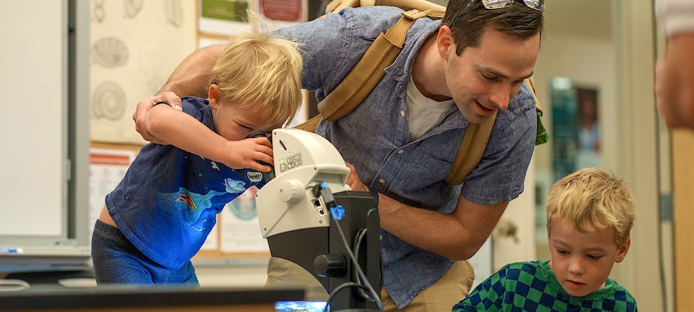 Parent with Children Looking at Microscope and Petri Dish