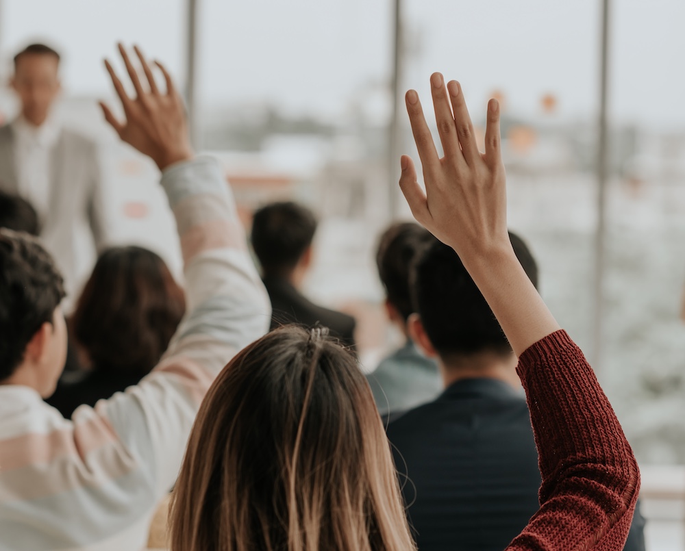 People Holding up Hands in Council Meeting