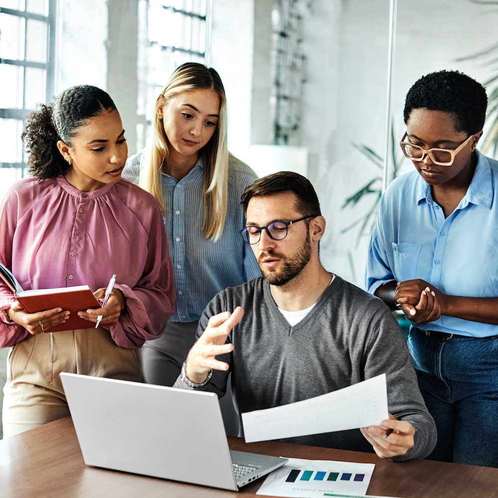 Group Discussing Ideas Around Person Sitting at Laptop