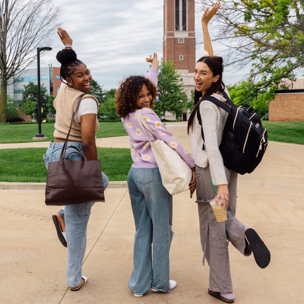 three students outdoors on college campus posing for photo