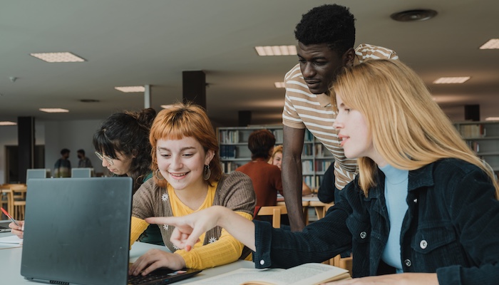 Students Looking at the Same Laptop Together in the Library