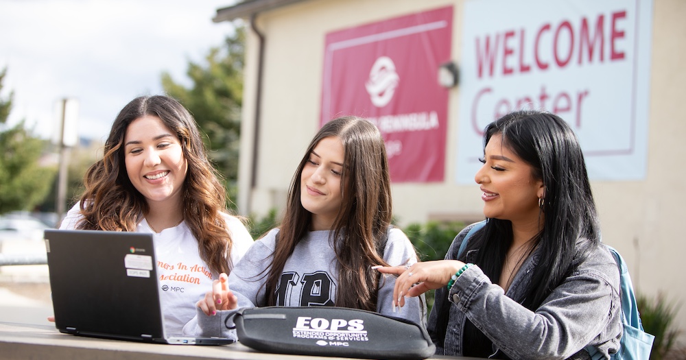 Three Students Looking at One Laptop Together