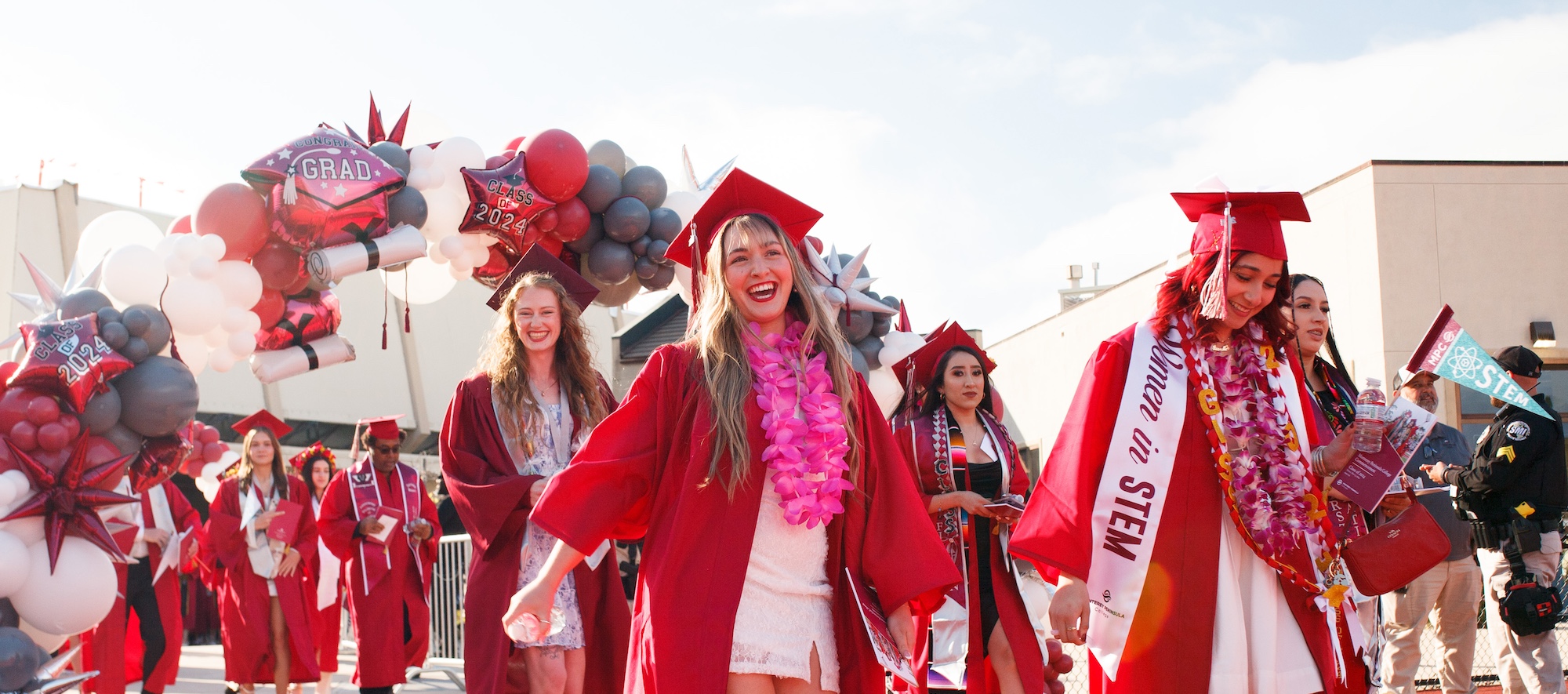 MPC Students Smiling and Walking at Graduation under Balloon Arch