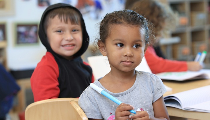 Two Children Sitting Down Inside at Table